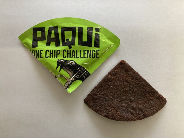 A Paqui One Chip Challenge chip is displayed in Boston, Friday, Sept. 8, 2023. The death of a Massachusetts teenager after his family said he ate an extremely spicy tortilla chip has led to an outpouring of concern about the social media challenge and prompted retailers to pull the product from their shelves at the manufacturer's request. (AP Photo/Steve LeBlanc)