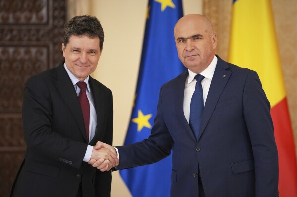 Romanian President Nicusor Dan, left, shakes hands with Ilie Bolojan, the President of the country's senate, after nominating him as the new Prime Minister at the Cotroceni Presidential Palace in Bucharest, Romania, Friday, June 20, 2025. (AP Photo/Andreea Alexandru)