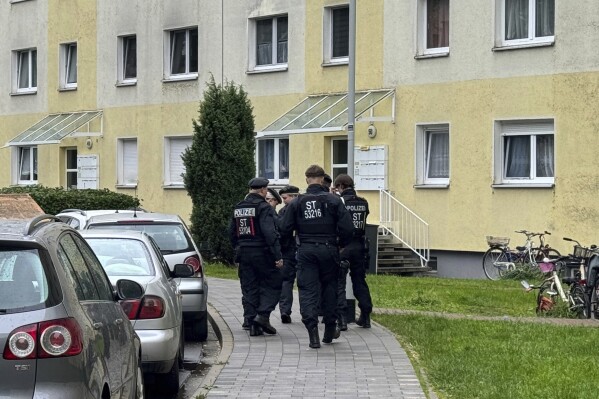 Police officers walk on a side walk next to an apartment building in Wolmirstedt, Germany, Saturday, June 15, 2024. German police say they shot to death an Afghan man after he fatally attacked a compatriot and later wounded three people watching the televised opening game of the Euro 2024 soccer tournament in a town in the east of the country. The 27-year-old man attacked another Afghan with a “knife-like object” in Wolmirstedt, a small town about 130 kilometers west of Berlin, on Friday evening, police said. (Thomas Schulz/dpa via AP)