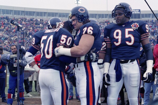 Chicago Bears nine-time Pro Bowler Mike Singletary (50) gets a bear hug from teammate Steve McMichael (76) prior to an NFL football game against the Pittsburgh Steelers in Chicago, Dec. 13, 1992. (AP Photo/David Boe, File)