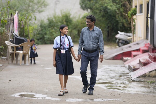 Gautam Dongre, right, of the National Alliance of Sickle Cell Organizations, and his daughter Sumedha, a patient of sickle cell disease walk through their neighborhood in Nagpur, India, Wednesday, Dec. 6, 2023. For many years, awareness of the disease has been lacking, he says, even among some health professionals. (AP Photo/Ajit Solanki)