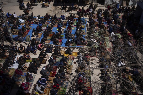 Palestinians perform the first Friday prayers of the Muslim holy month of Ramadan near the ruins of a destroyed mosque by the Israeli airstrikes in Rafah, Gaza Strip, Friday, March 15, 2024. (AP Photo/Fatima Shbair)