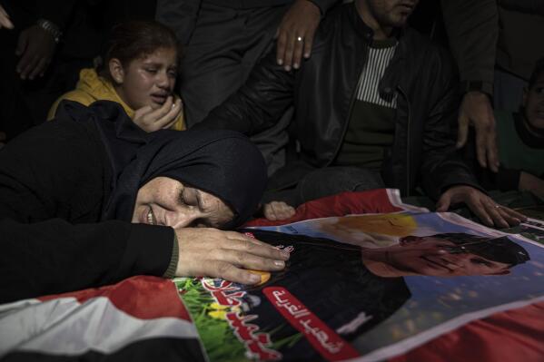 Mohammed al-Shaer's mother on his coffin during his funeral in Rafah, in the southern Gaza Strip, Sunday, Dec. 18, 2022. Thousands of people have joined the funerals of eight young Palestinian men who drowned off the coast of Tunisia nearly two months ago as they tried to sail to new lives in Europe. (AP Photo/Fatima Shbair)