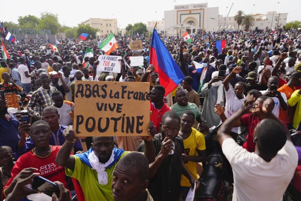 Nigeriens participate in a march called by supporters of coup leader Gen. Abdourahmane Tchiani in Niamey, Niger, Sunday, July 30, 2023. Days after mutinous soldiers ousted Niger's democratically elected president, uncertainty is mounting about the country's future and some are calling out the junta's reasons for seizing control. The sign reads: 