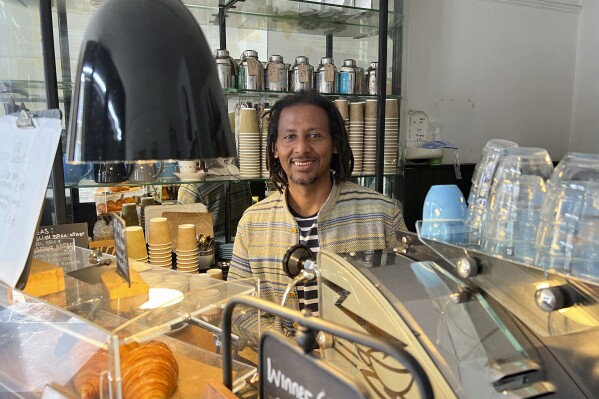 Anteneh Mulu, 46, poses behind the counter after serving a customer at his coffee shop, The Ethiopian Coffee Company, in central London on Thursday, Aug. 31, 2023. Mulu and his business partner Polly Hamilton, 79, opened their shop in 2013. The London-based International Coffee Organization has declared this Sunday, Oct. 1, as International Coffee Day. (AP Photo/Almaz Abedje)
