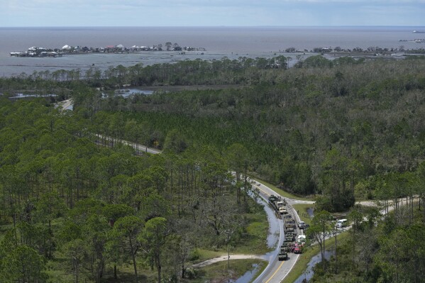 In this photo made in a flight provided by mediccorps.org, National Guardsmen and other first responders gather on a road leading to Keaton Beach and Dark Island, back left, near Fish Creek, Fla., following the passage of Hurricane Idalia, Wednesday, Aug. 30, 2023. (AP Photo/Rebecca Blackwell)