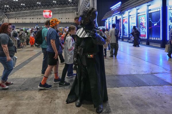 A Star Wars fan dressed as Darth Vader tries to demonstrate the Force during a fan convention called the Star Wars Celebration Japan in Chiba, near Tokyo, Friday, April 18, 2025. (AP Photo/Hiro Komae)