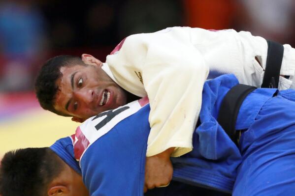 FILE - In this Thursday, Aug. 30, 2018, file photo, Saeid Mollaei of Iran, top, competes against Didar Khamza of Kazakhstan during their men's - 81kg final judo match at the18th Asian Games in Jakarta, Indonesia. A group of athletes and human rights activists is calling on the IOC to sanction Iran's Olympic program for what it says is the country's long-running pattern of ordering athletes to avoid competing against Israelis in international events. Last month, the Court of Arbitration for Sport overturned Iran's suspension from international judo events in a case stemming from former world champion Saeid Mollaei's departure from the Iranian team; Mollaei had claimed he was ordered to lose matches and withdraw from competitions to avoid facing Israelis. (AP Photo/Tatan Syuflana, File)