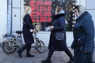 FILE - People walk past a currency exchange office screen displaying the exchange rates of U.S. Dollar and Euro to Russian Rubles in Moscow, on Feb. 28, 2022. (AP Photo/Pavel Golovkin, File)