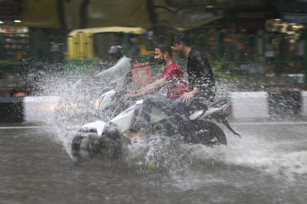 FILE - A motorcyclist drives through a water logged street during a heavy downpour in New Delhi, India, July 9, 2023. Scientists have long warned that more extreme rainfall is expected in a warming world. (AP Photo/Manish Swarup, File)