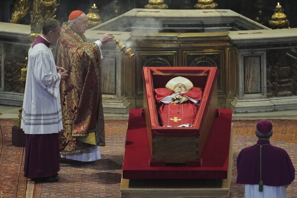 Cardinal Camerlengo Kevin Joseph Farrell asperges incense around the body of Pope Francis inside St. Peter's Basilica at the Vatican, Wednesday, April 23, 2025, where he will lie in state for three days. (AP Photo/Andrew Medichini, Pool)