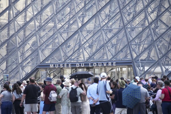 Tourists wait outside the Louvre museum which failed to open on time Monday, June 16, 2025 in Paris. (AP Photo/Christophe Ena)