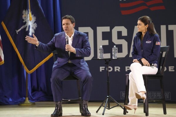 Florida Gov. Ron DeSantis, left, speaks during an event for his GOP presidential campaign as his wife Casey DeSantis looks on, on Friday, Dec. 1, 2023, in Prosperity, S.C. DeSantis is making a daylong swing through South Carolina, which holds the first southern Republican presidential primary of the 2024 campaign. (AP Photo/Meg Kinnard)