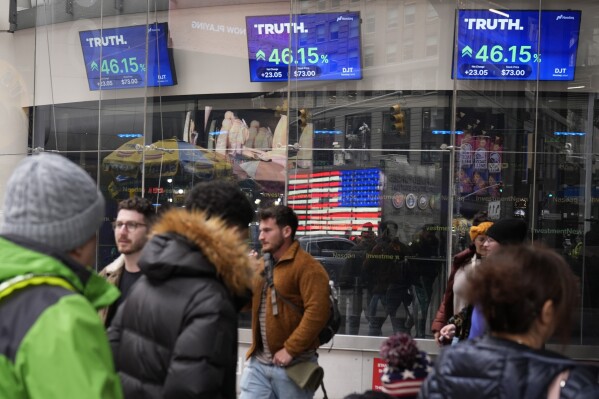 FILE - Pedestrians walk past the Nasdaq building Tuesday, March 26, 2024, in New York with the stock price of Trump Media & Technology Group Corp., displayed on screens. (AP Photo/Frank Franklin II, File)