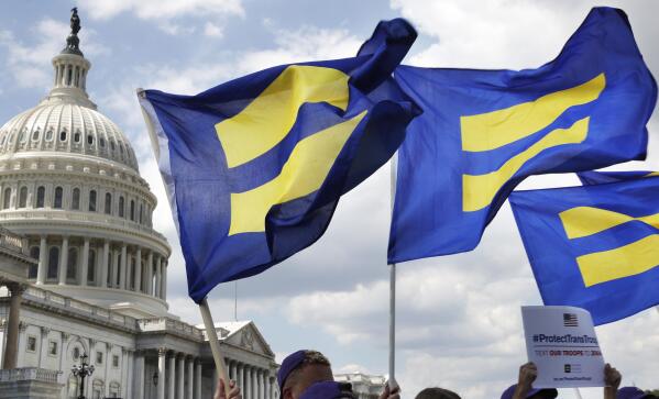 FILE - People with the Human Rights Campaign hold up "equality flags" during an event on Capitol Hill on July 26, 2017, in Washington, in support of transgender members of the military. The Human Rights Campaign declared a state of emergency for LGBTQ+ people in the U.S. on Tuesday, June 6, 2023, and a released “a guidebook for action” summarizing what it calls discriminatory laws in each state, along with “know your rights” information and health and safety resources. (AP Photo/Jacquelyn Martin, File)