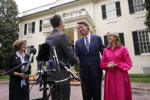 Virginia Gov. Ralph Northam, second from left, shakes the hand of Gov. Elect Glenn Youngkin, second from right, as Suzanne Youngkin, right, and Pam Northam look on after a transition meeting outside the Governors Mansion at the Capitol in Richmond, Va., Thursday, Nov. 4, 2021. (AP Photo/Steve Helber)