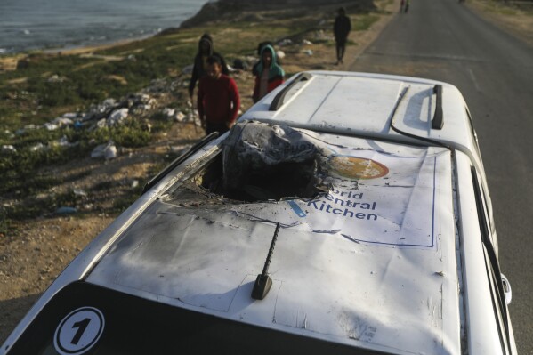 Palästinenser inspizieren ein Fahrzeug mit dem World Central Kitchen-Logo, das durch einen israelischen Luftangriff in Deir al Balah, Gazastreifen, am 2. April 2024 zerstört wurde. (AP Photo/Ismael Abu Dayyah)