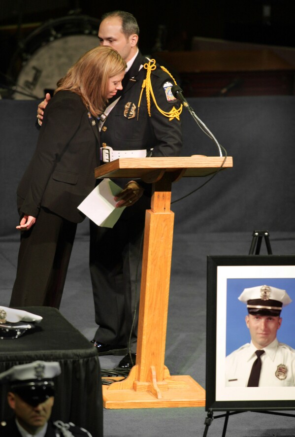 Marissa Hurst, wife of slain officer Bryan Hurst, left, hugs Sgt. Donnie Oliverio, after Oliverio paid tribute to Bryan, during a service in Columbus, Ohio, on Jan. 11, 2005. (Fred Squillante/The Columbus Dispatch via AP, File)