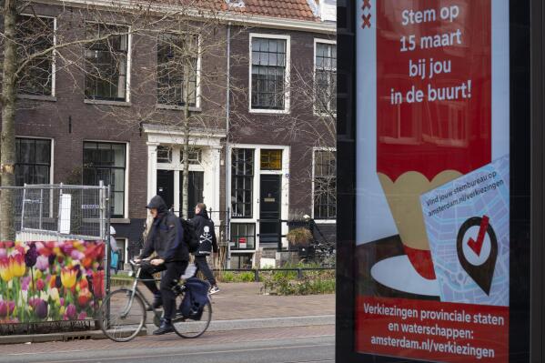 An electronic billboard calls on people to vote in the March 15 provincial election as a bicyclist passes in Amsterdam, Netherlands, Monday, March 13, 2023. (AP Photo/Peter Dejong)