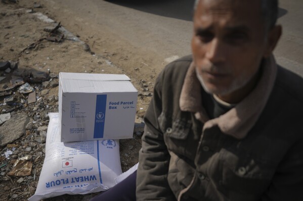 A Palestinian man takes a break while carrying UN donated flour in Khan Younis, central Gaza Strip, Saturday Dec. 14, 2024.(AP Photo/Abdel Kareem Hana)