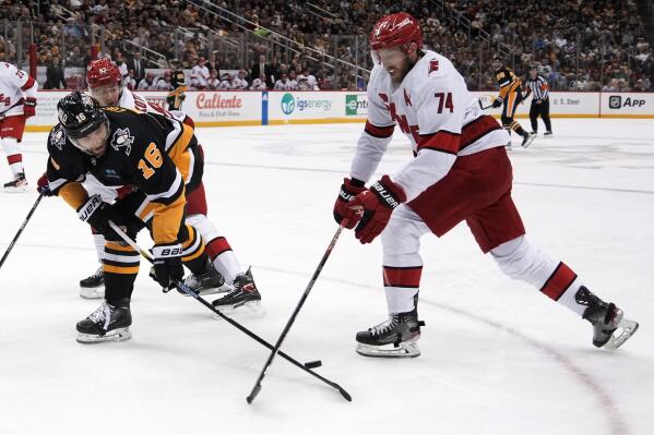 Carolina Hurricanes' Jaccob Slavin (74) knocks the puck off the stick of Pittsburgh Penguins' Jason Zucker (16) during the second period of an NHL hockey game in Pittsburgh, Thursday, Dec. 22, 2022. (AP Photo/Gene J. Puskar)