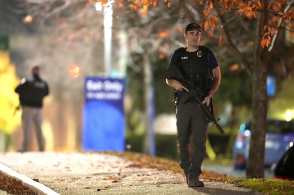 Law enforcement officers carry rifles outside Central Maine Medical Center during an active shooter situation, in Lewiston, Maine, Wednesday, Oct. 25, 2023. An independent commission investigating the deadliest shooting in Maine, that left 18 dead, released their interim report on Friday, March 15, 2024. (AP Photo/Steven Senne, File)
