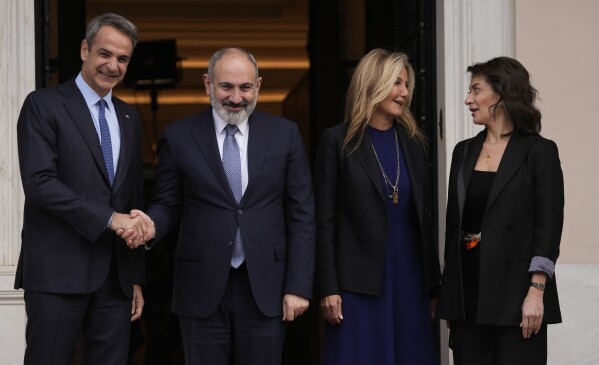 Greece's Prime Minister Kyriakos Mitsotakis, left, shakes hands with his Armenian counterpart Nikol Pashinyan as their wives Mareva Grabowski-Mitsotakis, second right, and Anna Hakobyan talk before their meeting at Maximos Mansion in Athens, Greece, Tuesday, Feb. 27, 2024. (AP Photo/Thanassis Stavrakis)