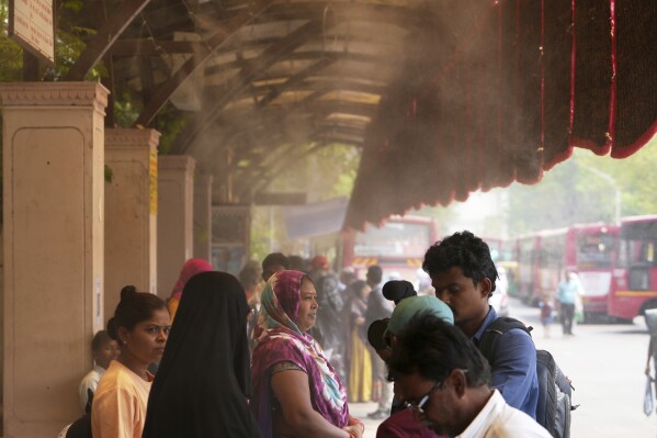 People wait for a bus at a cool bus stop in Ahmedabad, India, Wednesday, April 2, 2025. (AP Photo/Ajit Solanki)