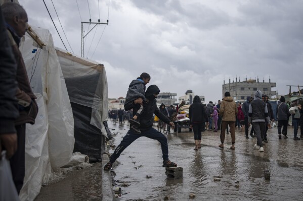Palestinians displaced by the Israeli air and ground offensive on the Gaza Strip walk through a makeshift tent camp in Rafah on Saturday, Jan. 27, 2024. (AP Photo/Fatima Shbair)