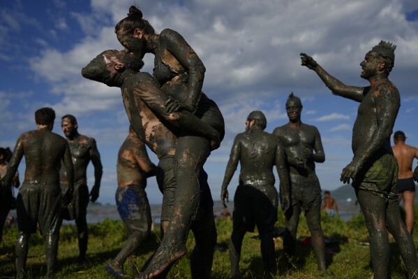 Revelers share a kiss during the traditional Mud Block carnival party in Paraty, Brazil, Saturday, March 1, 2025. (AP Photo/Andre Penner)