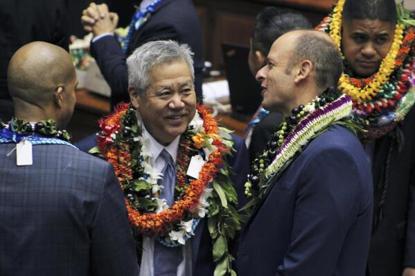House Speaker Scott Saiki, center, speaks to Rep. Luke Evslin, right, and Rep. Justin Woodson, left, on the floor of the Hawaii House of Representatives on the last day of the 2023 legislative session in Honolulu on Thursday, May 4, 2023. Hawaii lawmakers ended their 2023 legislative session on Thursday without allocating money for the tourism agency that manages the state's biggest industry and employer but legislators said some money would likely be made available to the Hawaii Tourism Authority through a process that will have Gov. Josh Green's administration and lawmakers vetting its funding requests. (AP Photo/Audrey McAvoy)