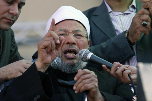 FILE -Senior Egyptian cleric Sheik Youssef al-Qardawi speaks to the crowd as he leads Friday prayers in Tahrir Square in Cairo, Egypt, Feb. 18, 2011. Al-Qardawi, a cleric who was seen as the spiritual leader of the pan-Arab Muslim Brotherhood, has died at the age of 96.  (AP Photo/Khalil Hamra, File)