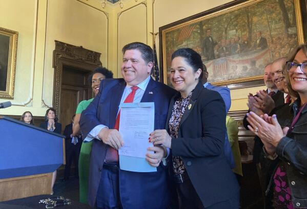 Illinois Gov. J.B. Pritzker, center left, and Comptroller Susana Mendoza smile at the state Capitol, in Springfield, Ill., Wednesday, May 10, 2023, after Pritzker signed a law providing disability benefits to Chicago first responders, including Mendoza's brother, who contracted COVID-19 on the job before vaccines were available. Pritzker said he was not worried about a $1.84 billion drop in revenue in April compared with a year earlier because the budget he proposed last winter for the fiscal year that begins July anticipated less revenue. The Legislature has to approve a spending plan before its scheduled spring session adjournment on Friday, April 19. (AP Photo/John O'Connor)