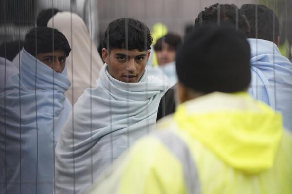 A view of people thought to be migrants inside the Manston immigration short-term holding facility located at the former Defence Fire Training and Development Centre in Thanet, Kent, England, Thursday, Nov. 3, 2022. Britain’s interior minister has visited immigration facilities on England’s southeastern coast as she grappled with an overcrowding crisis at a migrant facility and outcry over her claim that the U.K. faced an “invasion” of asylum-seekers. (Gareth Fuller/PA via AP)