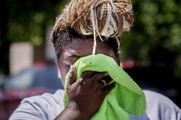 FILE - Nicole Brown wipes sweat from her face while setting up her beverage stand near the National Mall on July 22, 2022, in Washington. What's considered officially “dangerous heat” in coming decades will likely hit much of the world at least three times more often as climate change worsens, according to a new study. (AP Photo/Nathan Howard, File)