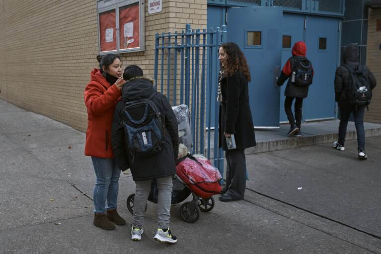 Migrant Karina Obando, 38 years old from Ecuador, left, and her 11-year-old son Efren Caiza, arrive at his school on Tuesday, Dec. 12, 2023, in New York. Obando who lives with Efren and her 3-year-old daughter Maily Caiza, in the Row Hotel that serves as migrant shelter, has received an eviction notice. It could be a cold, grim New Year for thousands of migrant families living in New York City’s emergency shelter system. With winter setting in, they are being told they need to clear out, with no guarantee they’ll be given a bed elsewhere. (AP Photo/Andres Kudacki)