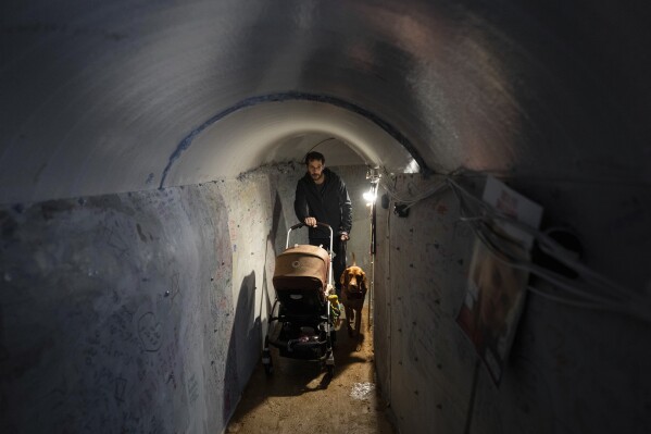 An Israeli man pushes a baby cart through an installation simulating a tunnel in Gaza in an act of solidarity with hostages believed to be held underground by Hamas and calling for their return, in Tel Aviv, Israel, Sunday, Jan. 14, 2024. (AP Photo/Oded Balilty)