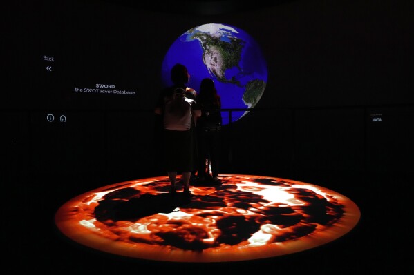 FILE - People look at artwork by Yiyun Kang at the COP28 U.N. Climate Summit, Sunday, Dec. 3, 2023, in Dubai, United Arab Emirates. (AP Photo/Peter Dejong, File)