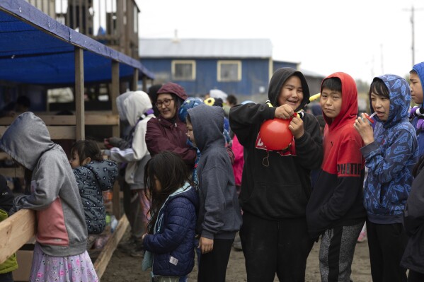 Maverick Chailes, 12, squeezes the air from a ballon at a friend while standing in line at the carnival, Thursday, Aug. 17, 2023, in Akiachak, Alaska. The village hosted a multiday carnival with games and prizes for the village youth. (AP Photo/Tom Brenner)