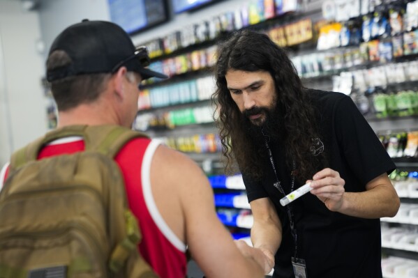 Cloud 9 Cannabis employee Beau McQueen, right, helps a customer, Saturday, April 13, 2024, in Arlington, Wash. The shop is one of the first dispensaries to open under the Washington Liquor and Cannabis Board's social equity program, established in efforts to remedy some of the disproportionate effects marijuana prohibition had on communities of color. (Ǻ Photo/Lindsey Wasson)