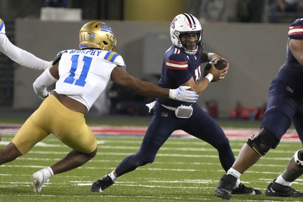 UCLA defensive lineman Gabriel Murphy (11) pressures Arizona quarterback Noah Fifita during the first half of an NCAA college football game Saturday, Nov. 4, 2023, in Tucson, Ariz. (AP Photo/Rick Scuteri)