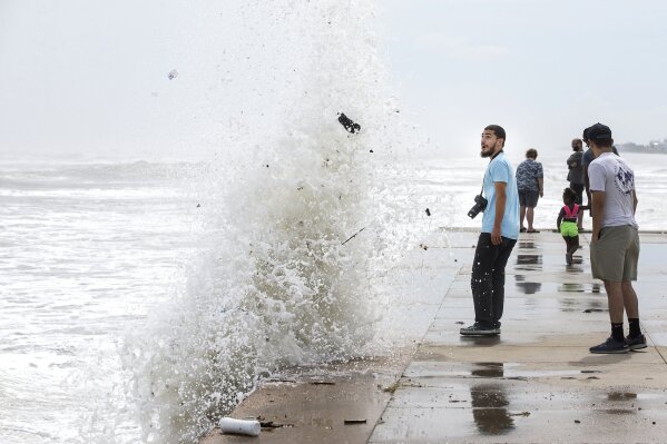 Jordan Razo steps back as a wave, stirred up by the approach of Hurricane Laura, crashes up and over the seawall Wednesday, Aug. 26, 2020 in Galveston, Texas. (Brett Coomer/Houston Chronicle via AP)