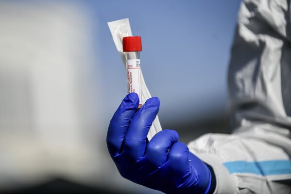 A medical personnel holds a kit for the test for Coronavirus outside one of the emergency structures that were set up to ease procedures outside the hospital of Brescia, Northern Italy, Tuesday, March 10, 2020. For most people, the new coronavirus causes only mild or moderate symptoms, such as fever and cough. For some, especially older adults and people with existing health problems, it can cause more severe illness, including pneumonia. (Claudio Furlan/LaPresse via AP)