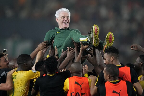 South Africa's head coach Hugo Broos is lifted up by players as they celebrate winning the penalty shootout during the African Cup of Nations third place soccer match between South Africa and DR Congo, at the Felix Houphouet-Boigny in Abidjan, Ivory Coast, Saturday, Feb. 10, 2024. (APPhoto/Sunday Alamba)