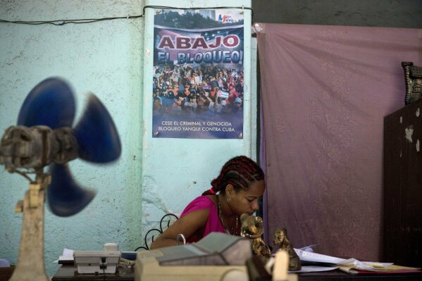
              A woman works in a government office where a sign hangs on the wall that reads in Spanish: "Down with the embargo" in Havana, Cuba, Wednesday, April 17, 2019. The Trump administration on Wednesday intensified its crackdown on Cuba, Nicaragua and Venezuela, rolling back Obama administration policy and announcing new restrictions and sanctions against the three countries whose leaders national security adviser John Bolton dubbed the “three stooges of socialism.” (AP Photo/Ramon Espinosa)
            