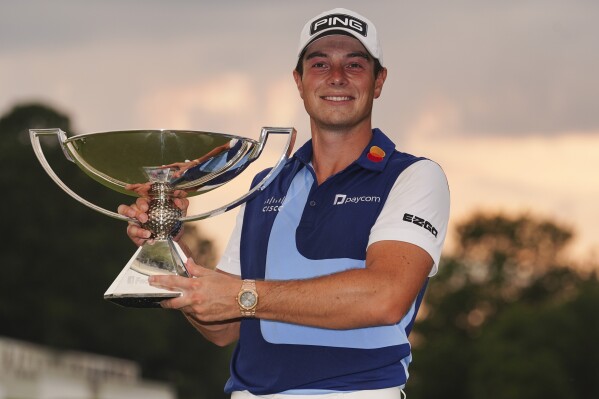 Viktor Hovland, of Norway, celebrates winning the Tour Championship golf tournament with the FedEx Cup trophy on the 18th green, Sunday, Aug. 27, 2023, in Atlanta. (AP Photo/John Bazemore)