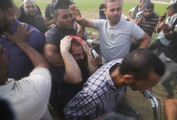 Palestinians transport a captured Israeli civilian, center, from Kibbutz Kfar Azza into the Gaza Strip during a deadly attack on the community, Saturday, Oct. 7, 2023. (AP Photo/Hatem Ali)