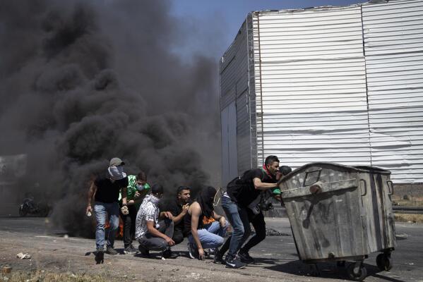 Palestinian demonstrators take cover during clashes with Israeli forces at the Hawara checkpoint, south of the West Bank city of Nablus, Friday, May 14, 2021. Health officials say several Palestinians were killed by Israeli army fire, at protests that took place in several locations across the West Bank of Friday. (AP Photo/Majdi Mohammed)