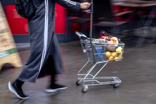 FILE - A woman pushes a small shopping cart outside a discount market in Frankfurt, Germany, on July 27, 2023. Inflation fell again in Europe in August, supporting market speculation that the European Central Bank might pause its record series of interest rate hikes. (AP Photo/Michael Probst, File)