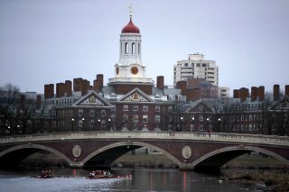 FILE - In this March 7, 2017 file photo, rowers paddle down the Charles River past the campus of Harvard University in Cambridge, Mass. A lawsuit alleging racial discrimination against Asian American applicants in Harvard's admissions process is heading to trial in Boston's federal court on Monday, Oct. 15, 2018. Harvard denies any discrimination, saying it considers race as one of many factors when considering applicants. (AP Photo/Charles Krupa, File)